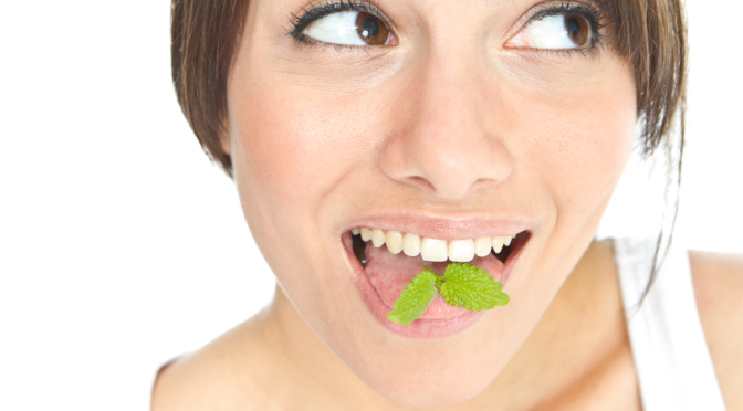 woman smiling with mint leaves on tongue